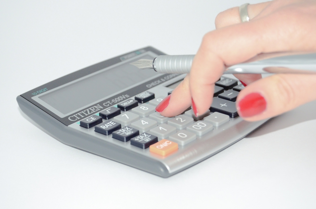 women with red painted nails using calculator
