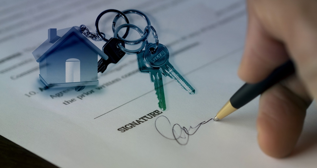 Contract being signed with a set of house keys on top of paper