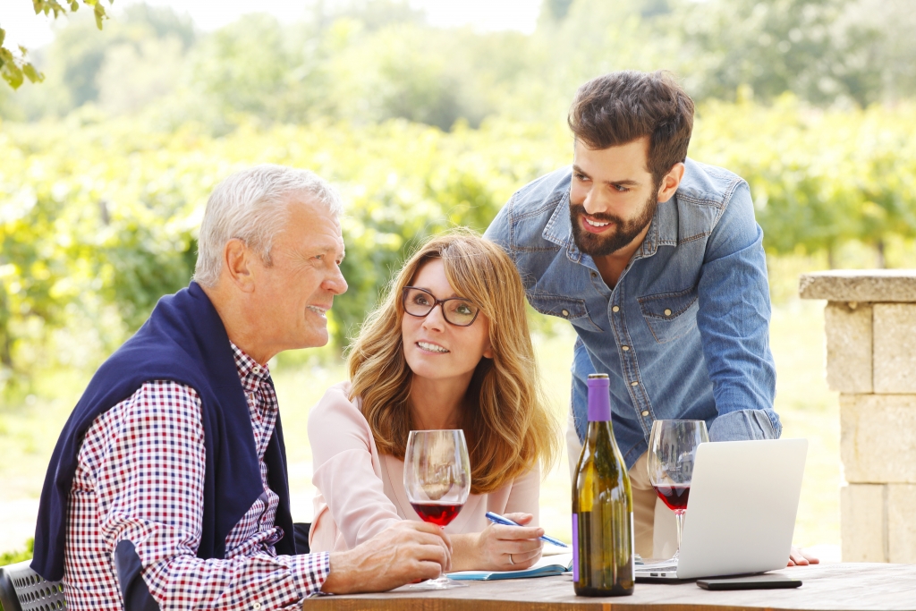 Elderly man sitting with younger middle age children in vineyard
