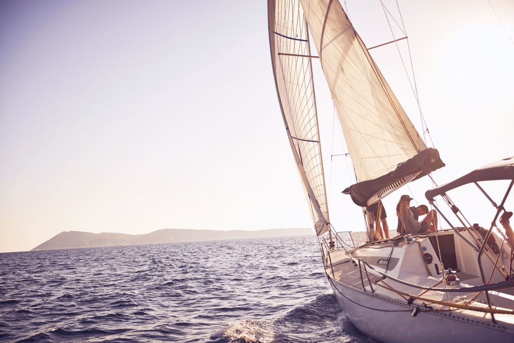 Sailboat in water heading towards an island during the day.