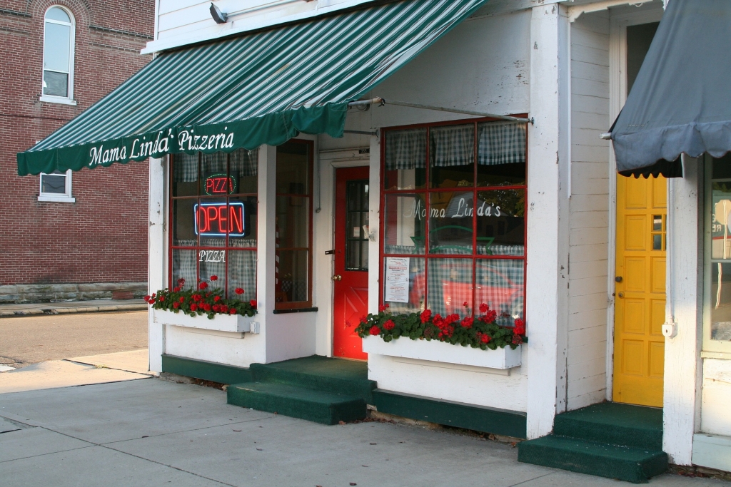 Front of White Building with Red Door and Green Roof. Open sign in window.