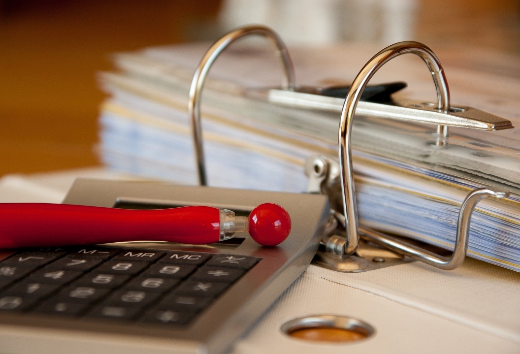 calculator on desk with red pen and binder