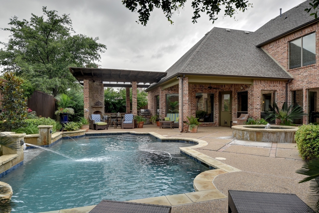 Inground pool in backyard with patio furniture and landscape