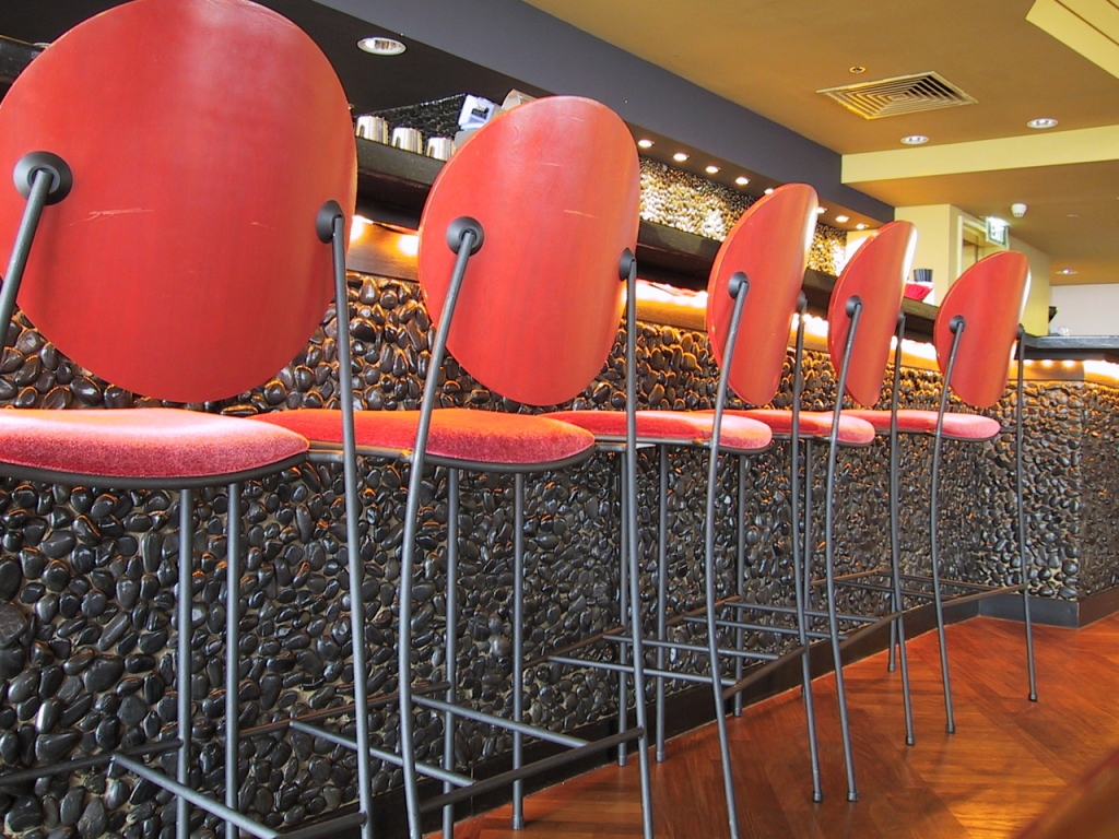 red bar chairs in front of a gray stone bar