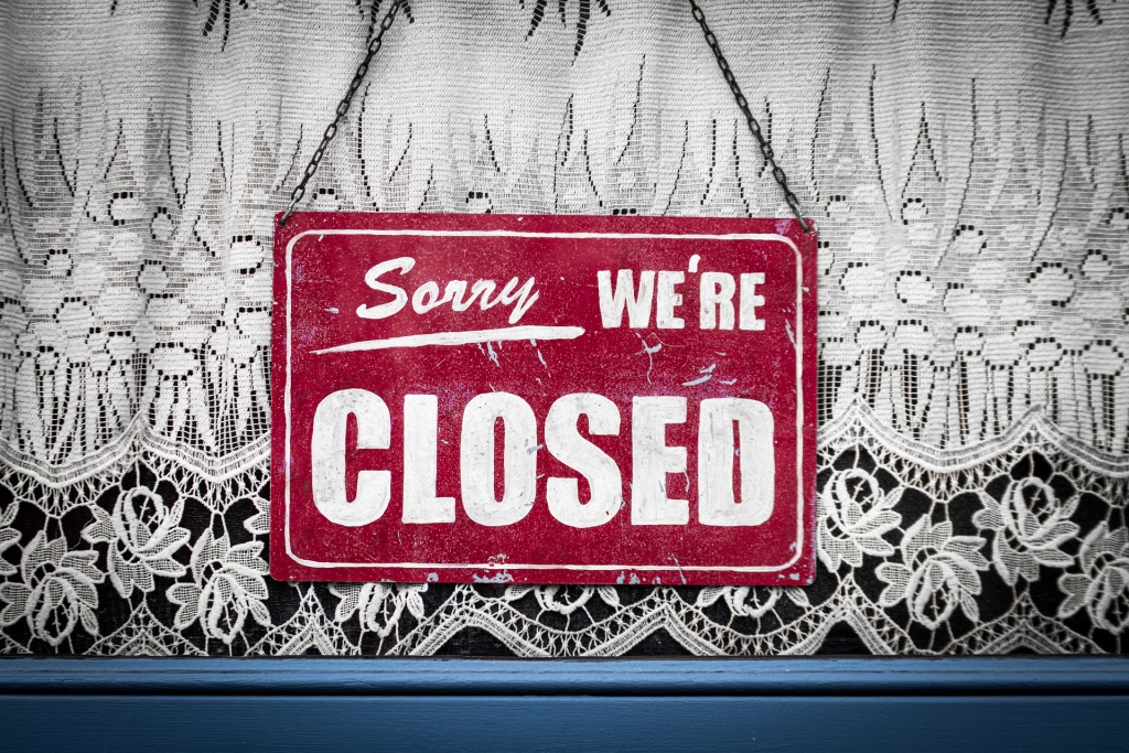 red closed sign hanging in store window
