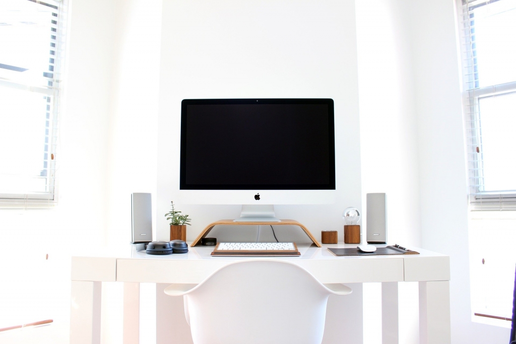 computer sitting on a white desk in a white room