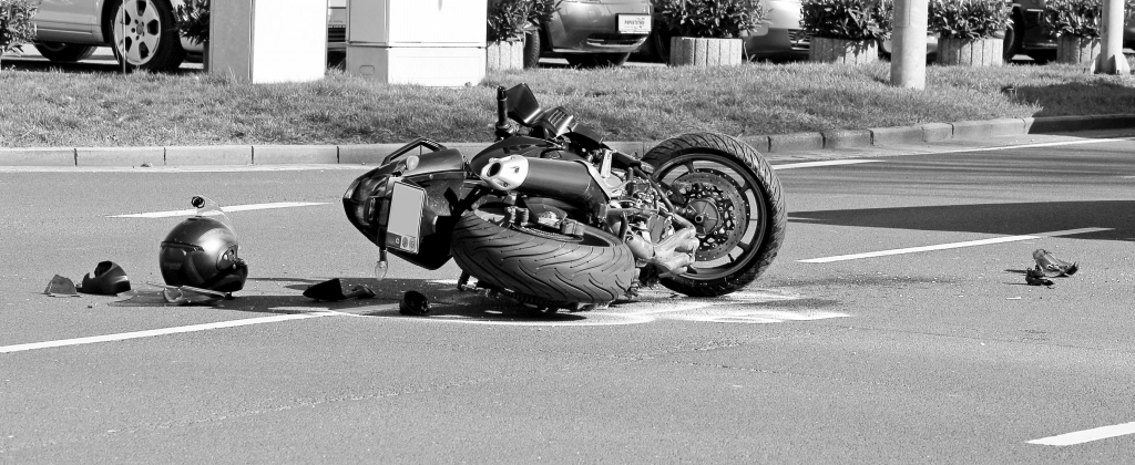 motorcycle laying on pavement. Photo black and white.