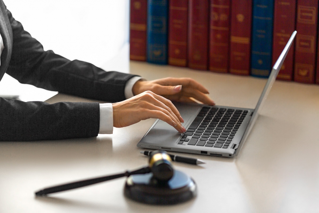 close up of lawyer typing on a laptop, books in background
