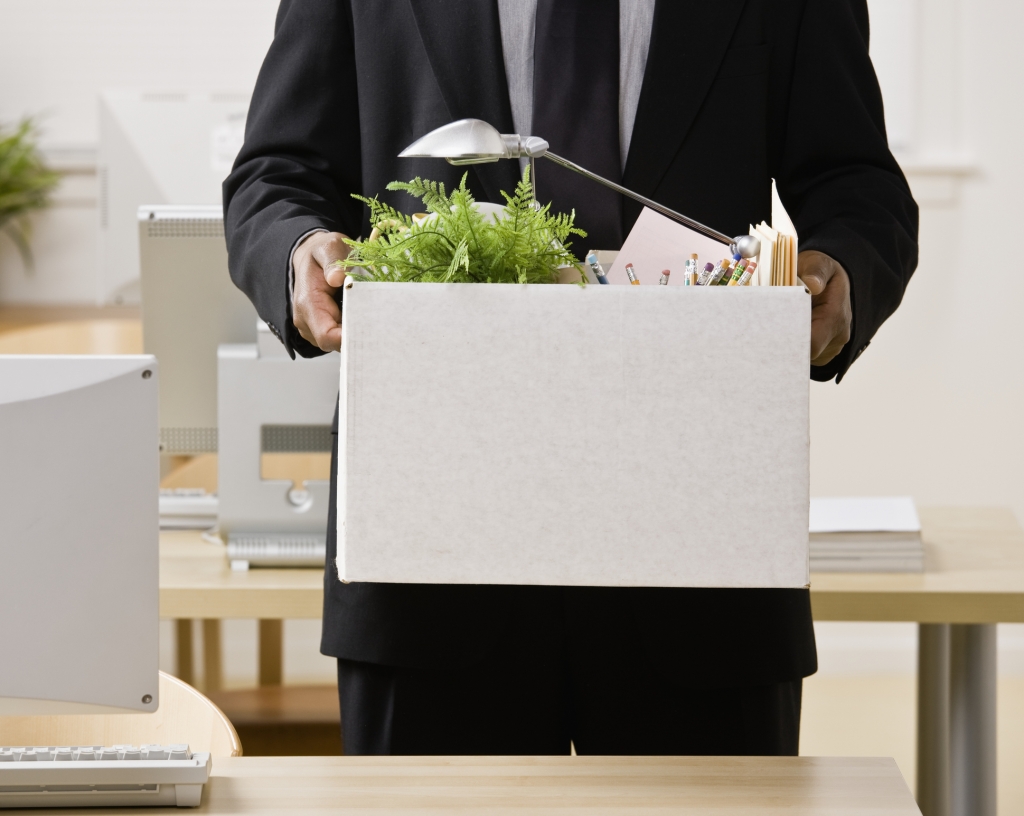 Fired businessman packing personal desk items in box