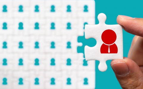 Hand holding piece of white jigsaw puzzle with icon. Human resource management and recruitment business concept