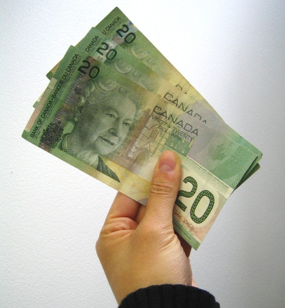 Hand holding several $20 Canadian bills