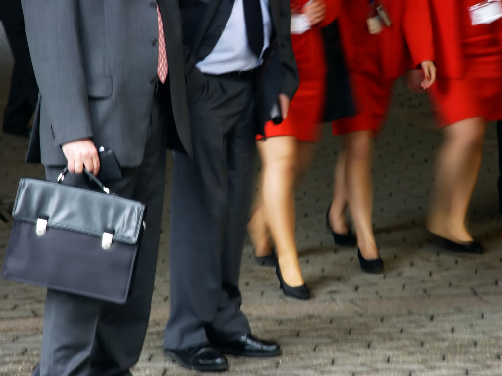 businessmen in suits and businesswomen in red skirts and black shoes. Close up of lower torso and feet.