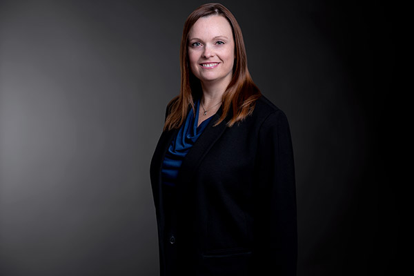 Professional photo of Lynne Vidal standing in front of a black gradient background.