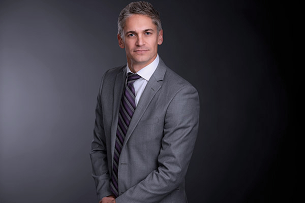 Professional photo of Mike Pychel standing in front of a black gradient background.