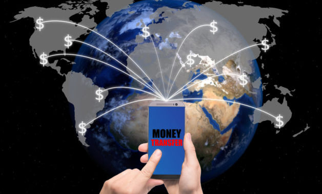 Hand holding smart phone sent money dollar bills flying away from screen to global map. Technology online banking money transfer, e-commerce concept.