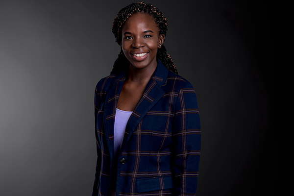 Professional photo of Ola Amuwo standing in front of a black gradient background.
