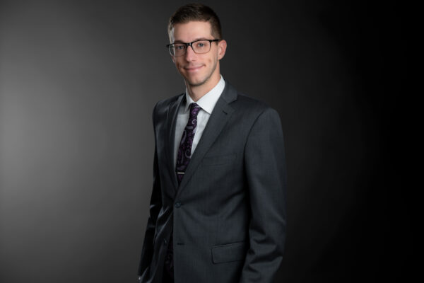 Professional photo of PJ Cole standing in front of a black gradient background.