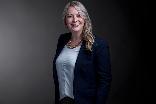 Professional photo of Trish Suess standing in front of a black gradient background