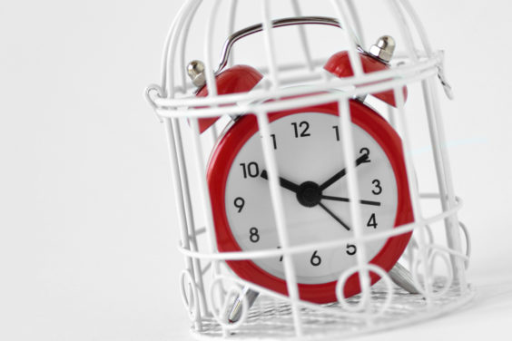 Close-up of red alarm clock in a cage - Concept of time limit