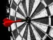 black and white dartboard with red dart in bullseye