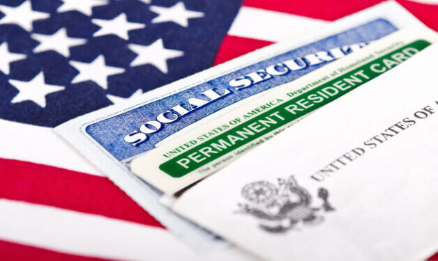 United States of America social security and green card with US flag on the background. Immigration concept. Closeup with shallow depth of field.