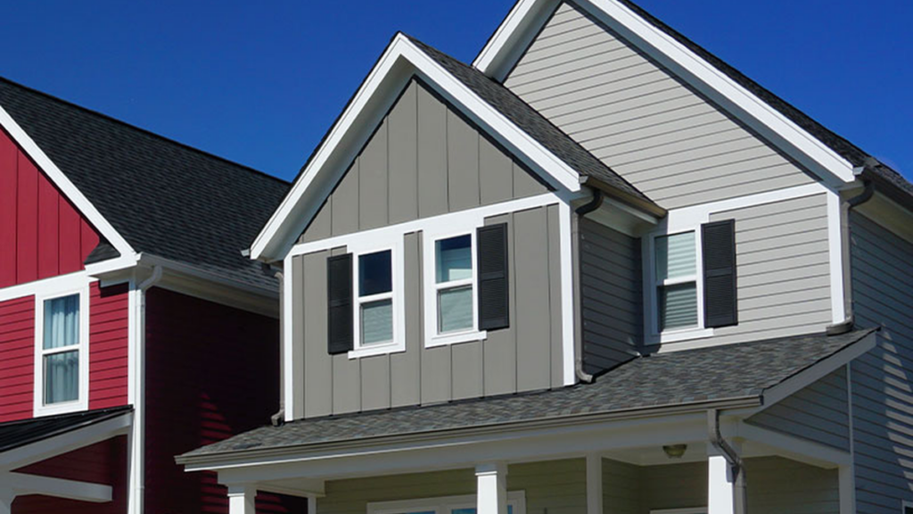 Close up of second story of a grey house with a red house on the left