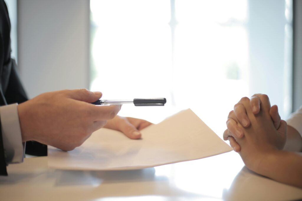 Closeup of person in business suit and another second set of hands exchanging paper work.