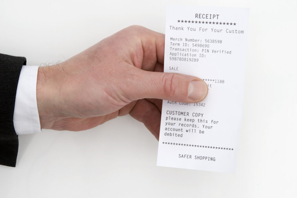 Picture of mans hand holding a receipt. The man is wearing a suit.