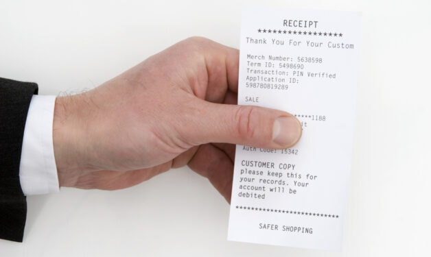 Picture of mans hand holding a receipt. The man is wearing a suit.