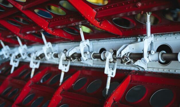 Close up of red & silver manufacturing machine.