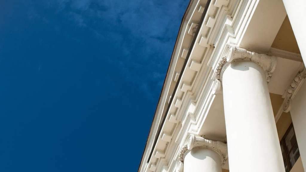 Top of building with columns. Building is white. Extreme close up.