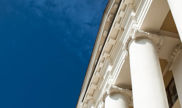 Top of building with columns. Building is white. Extreme close up.