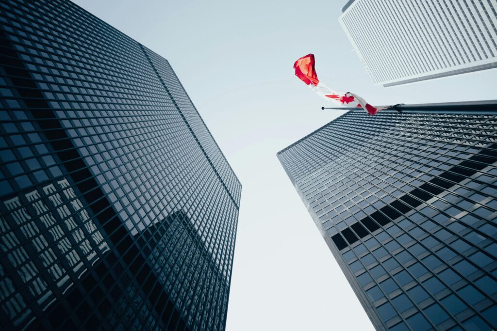 Image looking up at multiple office buildings. One building has a Canadian flag.