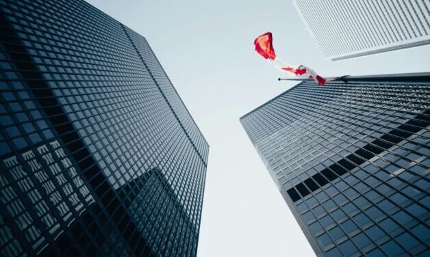 Image looking up at multiple office buildings. One building has a Canadian flag.