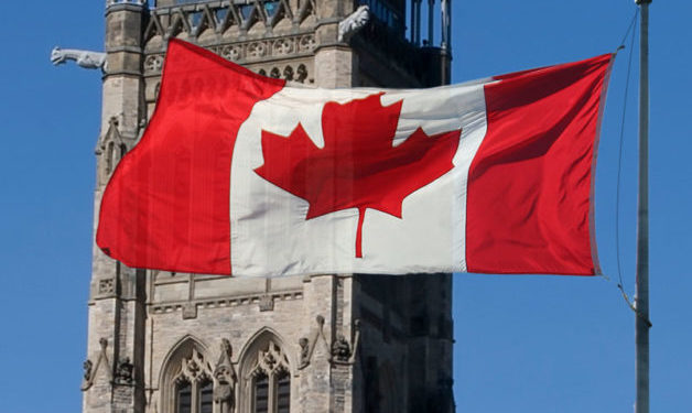 Close up of Canadian flag in front of a parliament building.