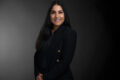 Professional photo of Ruchi Chawla standing in front of a black gradient background.