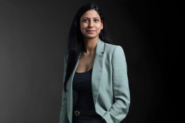 Professional photo of Harsha Yadav Malik standing in front of a black gradient background.