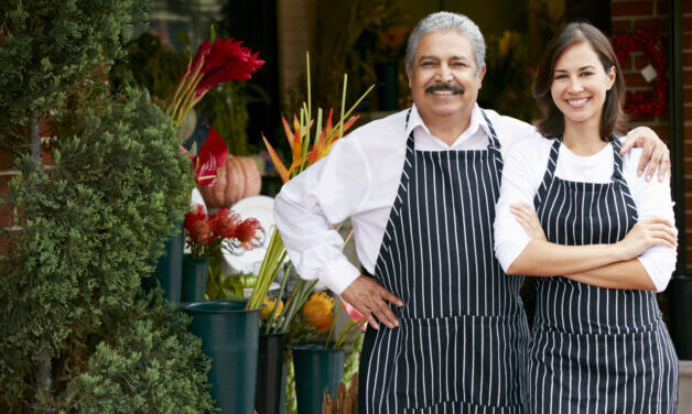 Portrait Of Male And Female Florist Outside Shop Smiling To Camera.