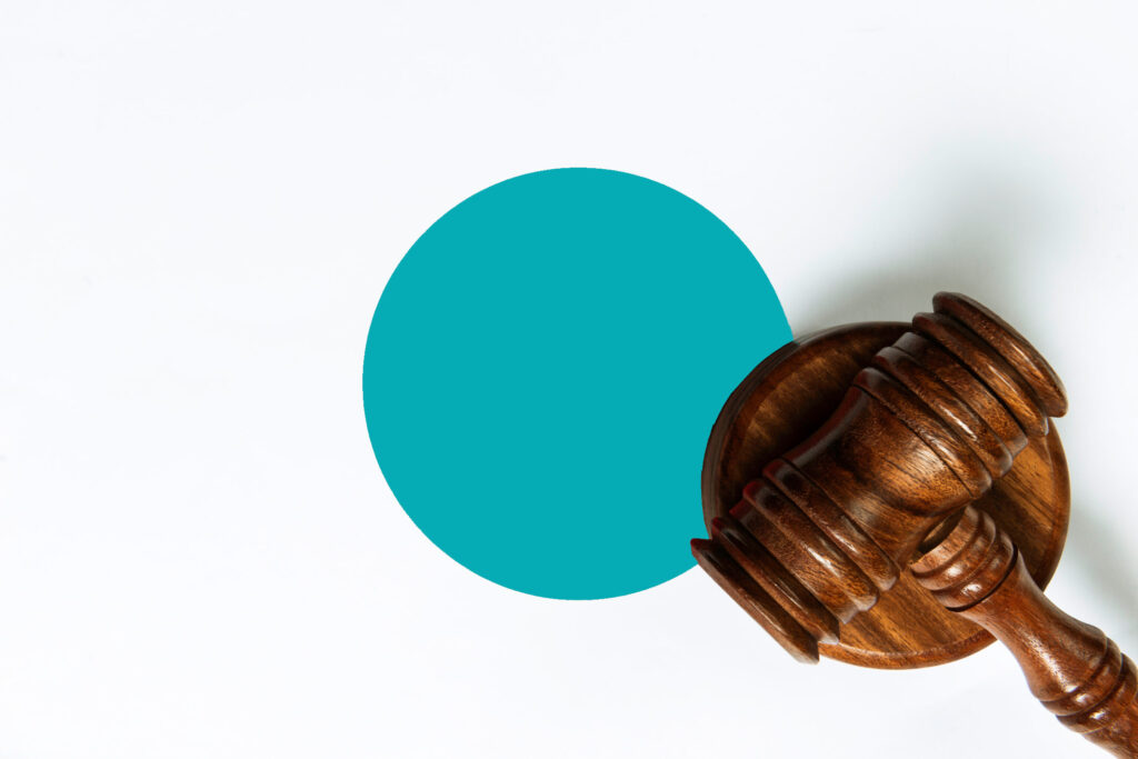 Brown gavel on a white background with a teal dot behind it.