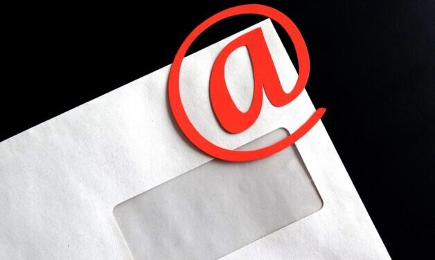 Closeup of white envelope with red @ symbol on corner. Black background.
