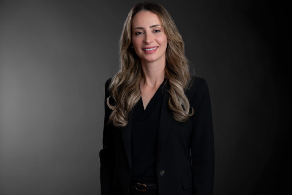 Professional photo of Kelly Paul standing in front of a black gradient background.