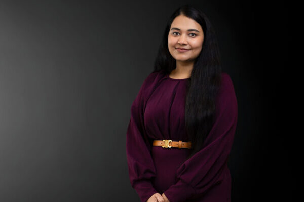 Professional photo of Simran Kaur standing in front of a black gradient background