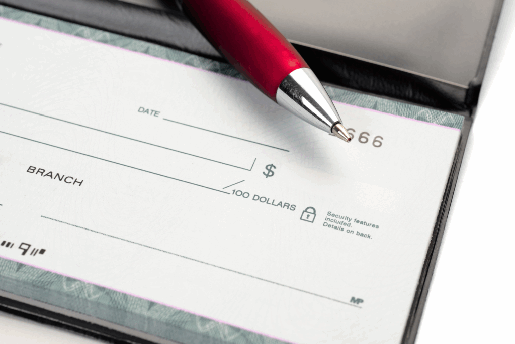 Close up of check book with a red pen sitting on top of it.