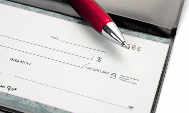 Close up of check book with a red pen sitting on top of it.