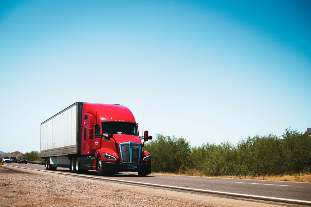 Red transport truck driving down a road.