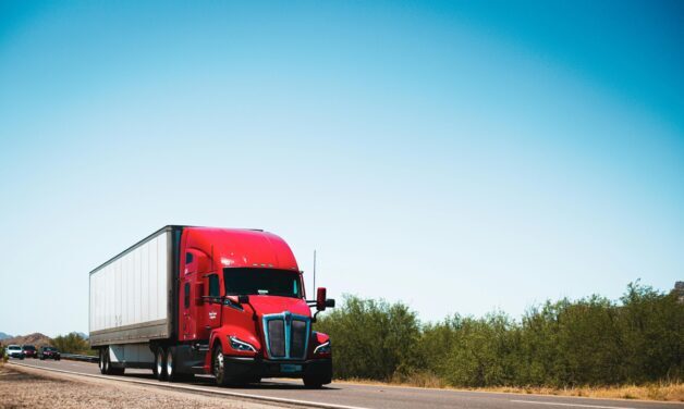 Red transport truck driving down a road.